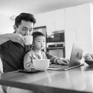 Dad on laptop with son on his lap 