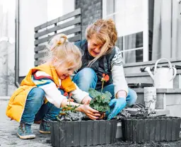 Child and grandmother planting flowers
