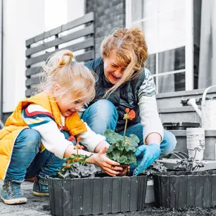 Child and grandmother planting flowers