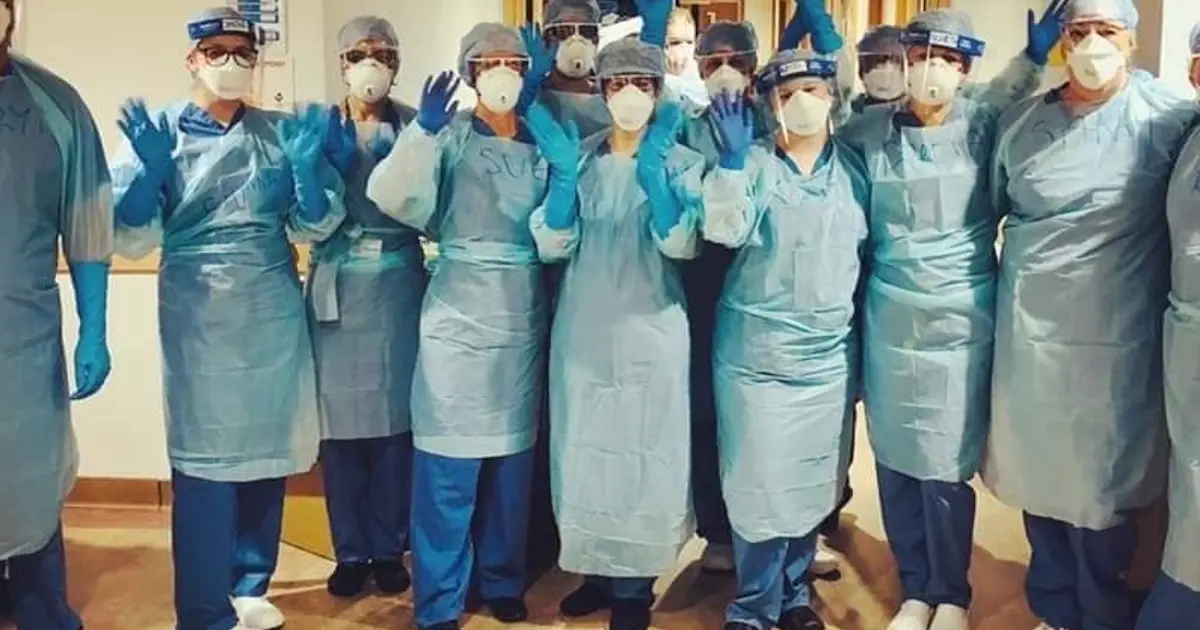 A group of NHS workers from Poole General Hospital wearing PPE face shields, gloves and aprons.