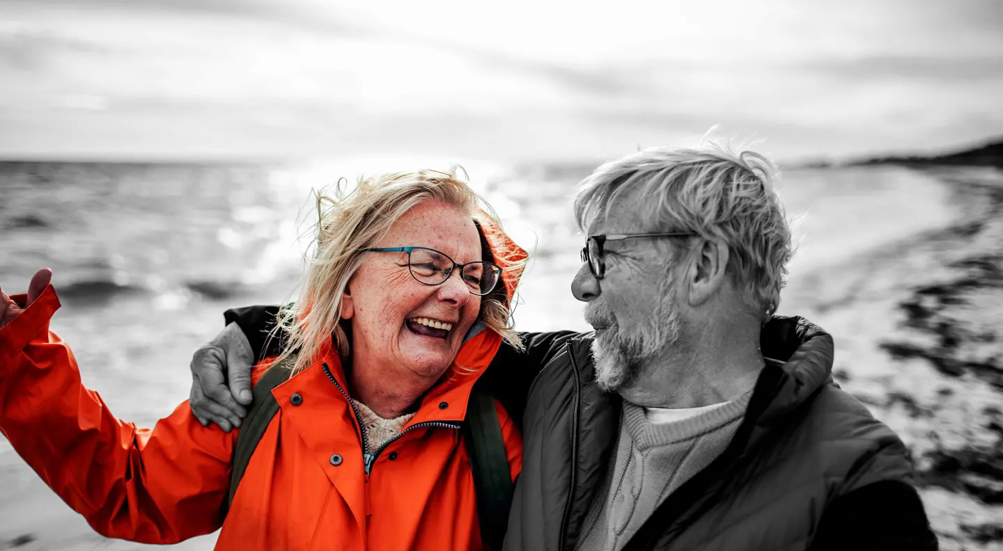 Two people wearing outdoor jackets walking together along a waterfront.