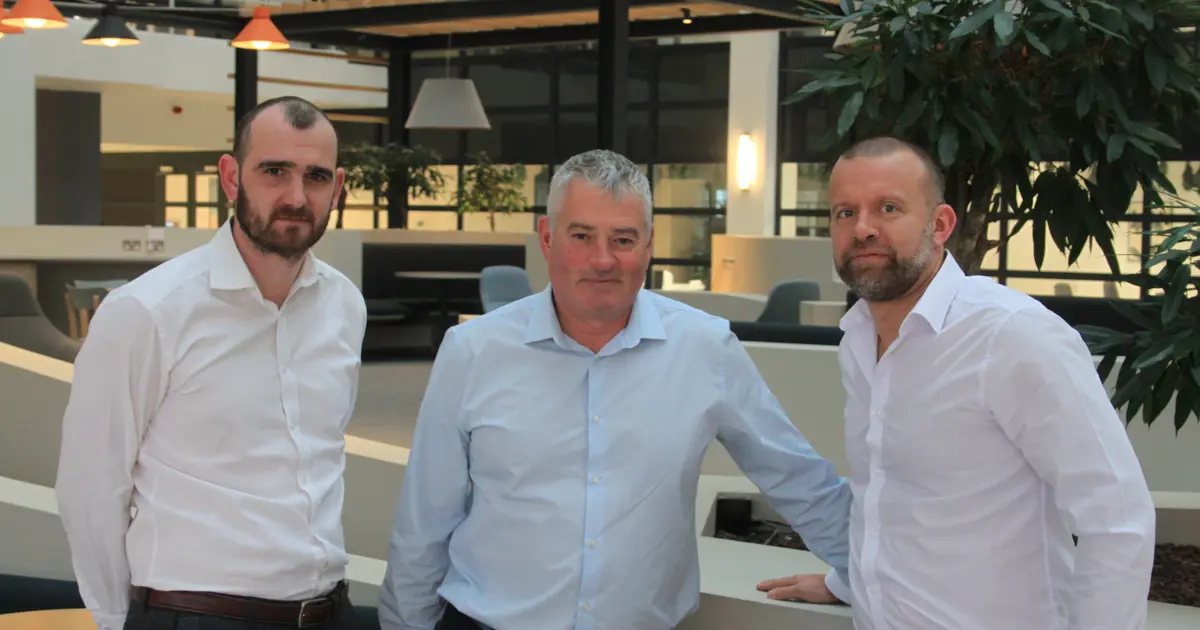 Three people from T&L Leasing standing in their modern office.