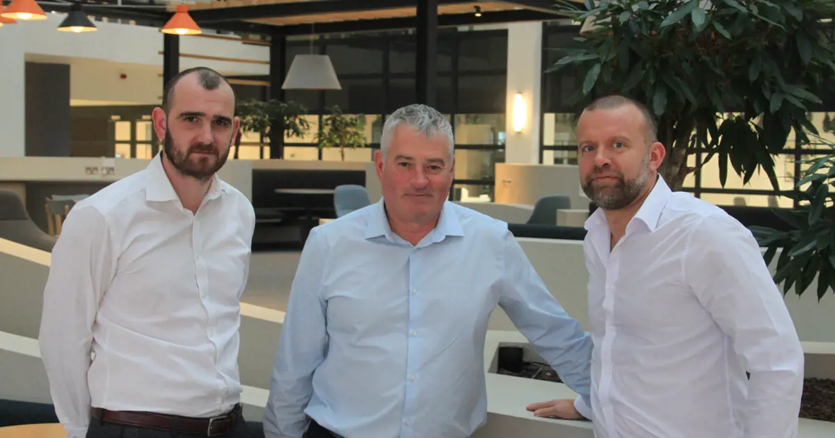 Three people from T&L Leasing standing in their modern office.