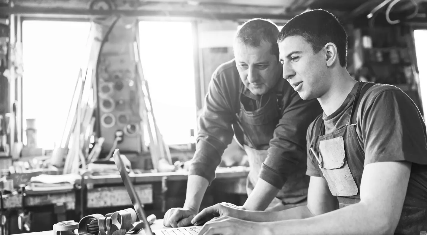 Mechanics looking at laptop in workshop 