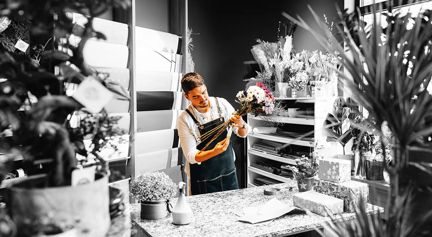 Independent florist creating a flower arrangement in a flower shop, showcasing small business, retail, and floral design services.