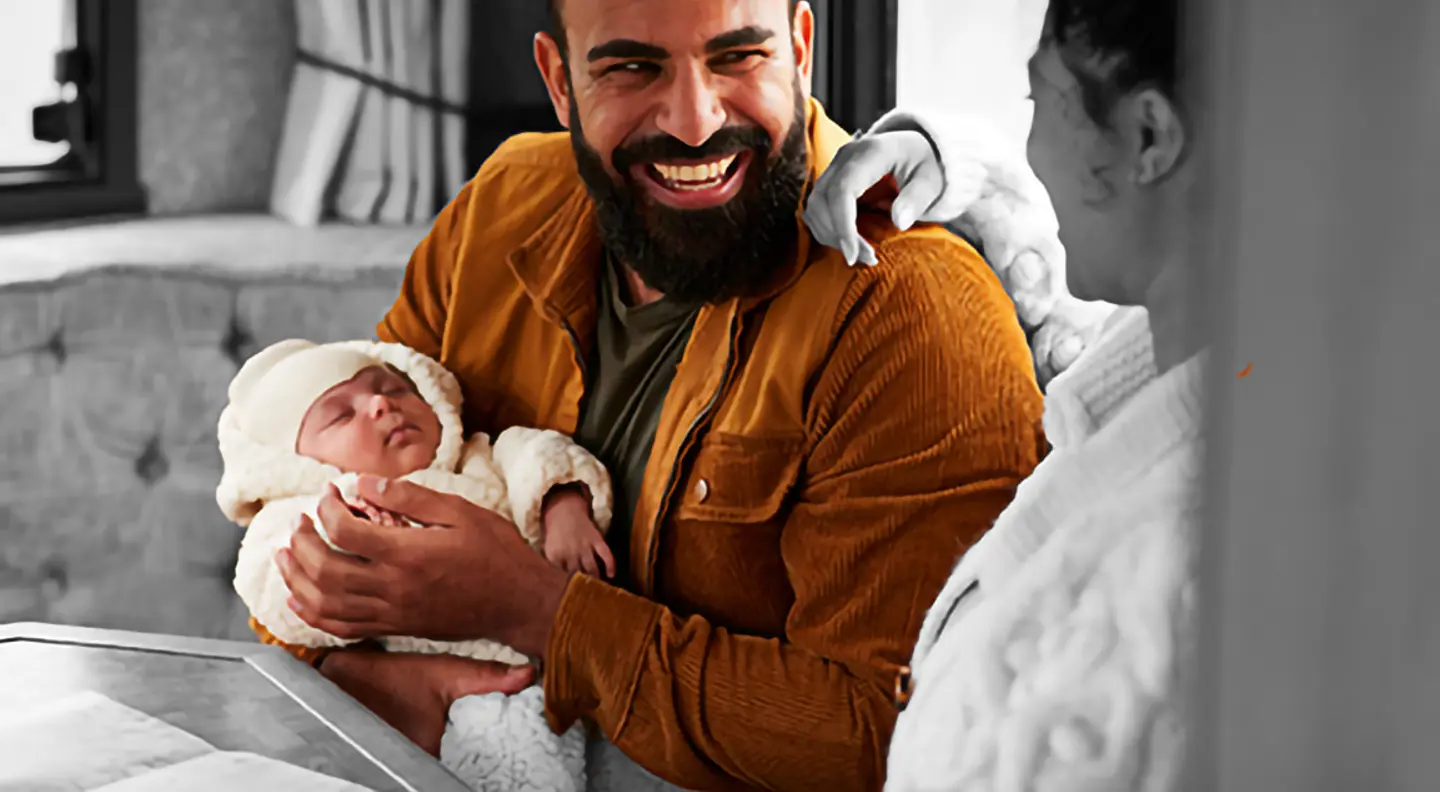 Person holding a baby while sitting with another child at a table indoors.
