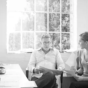 Two people sitting at desk reading papers