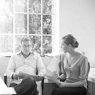 Two people sitting at desk reading papers