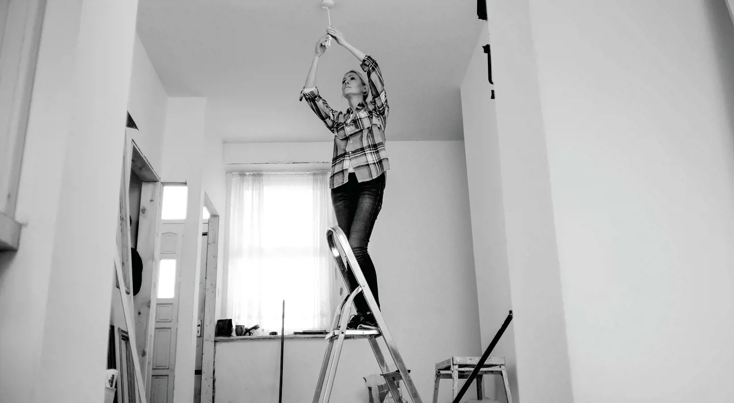 Person fixing lightbulb on ladder