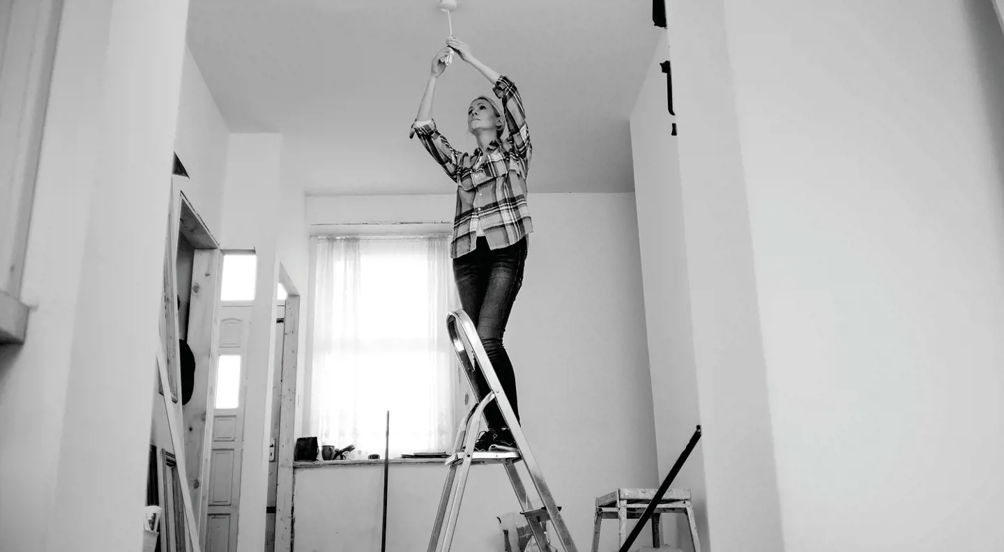Person fixing lightbulb on ladder 