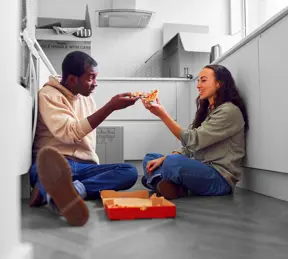 First time buyers eating pizza on floor 