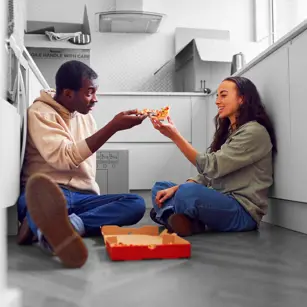 First time buyers eating pizza on floor 